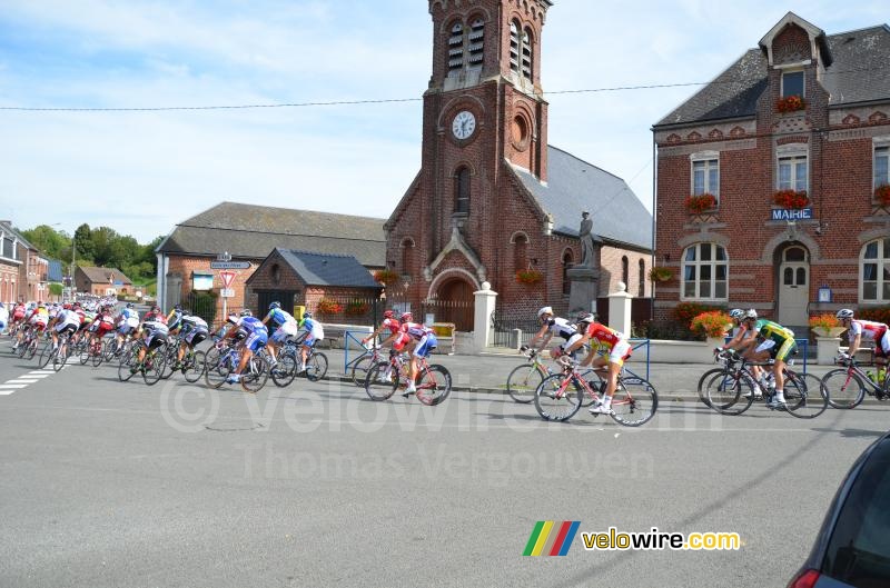 The peloton passes in front of the town hall and the church of Montay