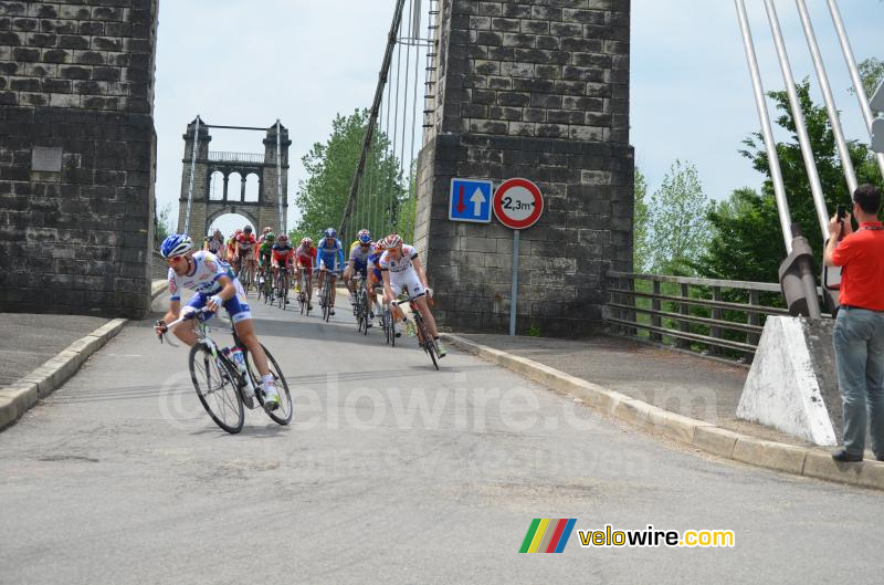 Het peloton rijdt over een brug