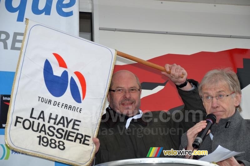 De burgemeester van La Haye Fouassière met een vlag van de start van een Tour de France etappe vanuit zijn gemeente