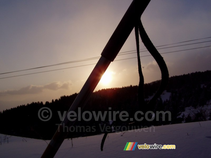 De zonsondergang achter een skistok