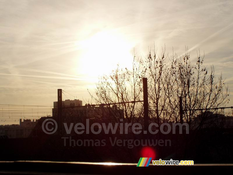 Opkomende zon boven de bomen en de spoorlijn