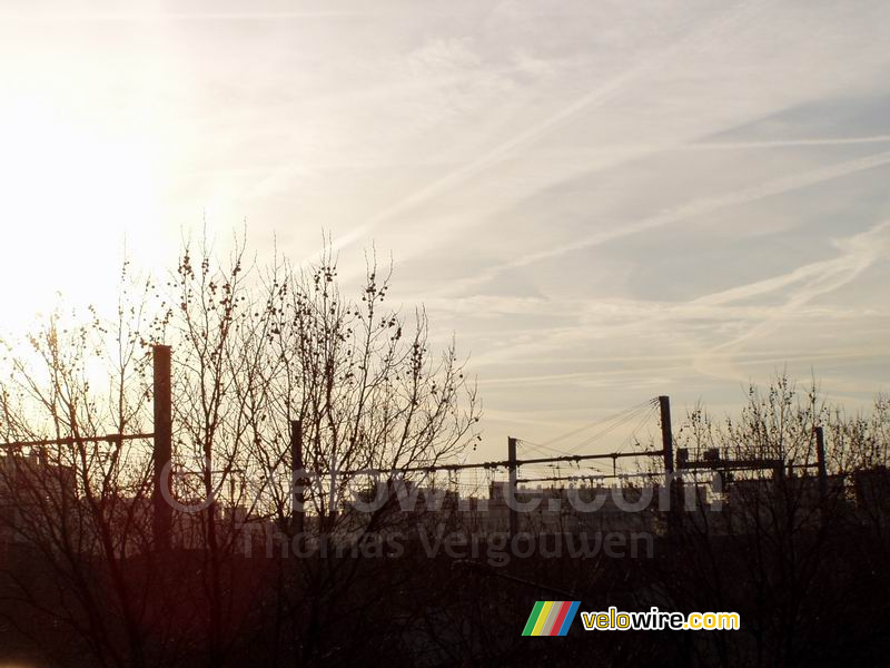 Opkomende zon boven de bomen en de spoorlijn