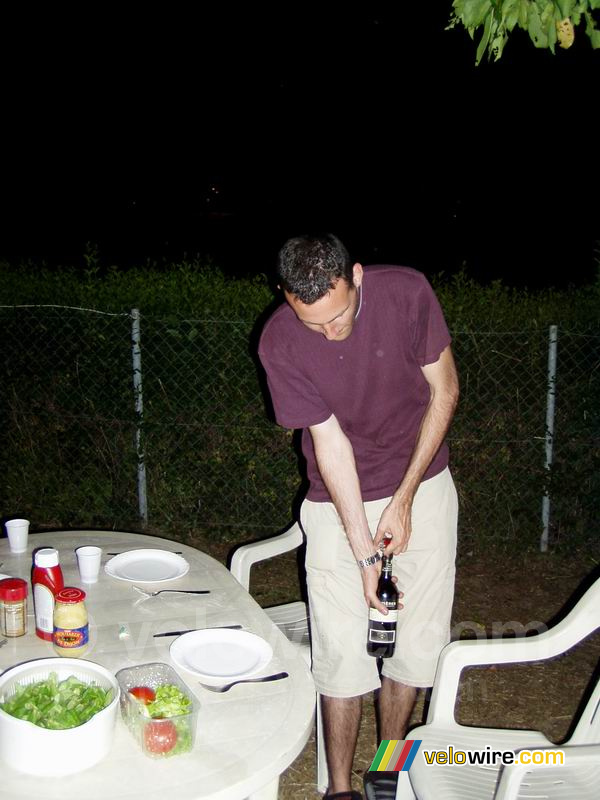 Bernie ouvre une bouteille de vin pendant le BBQ