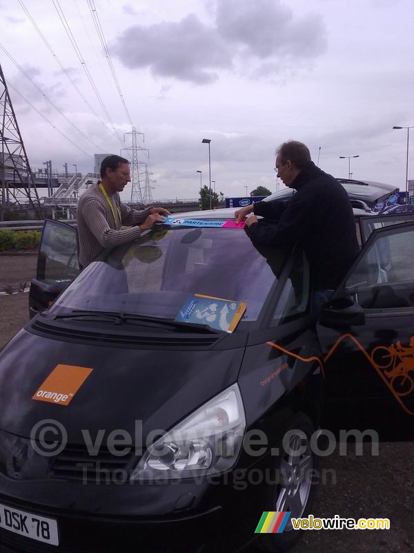 Eric Caritoux et Patrice Esnault plakken de sticker op de Orange auto