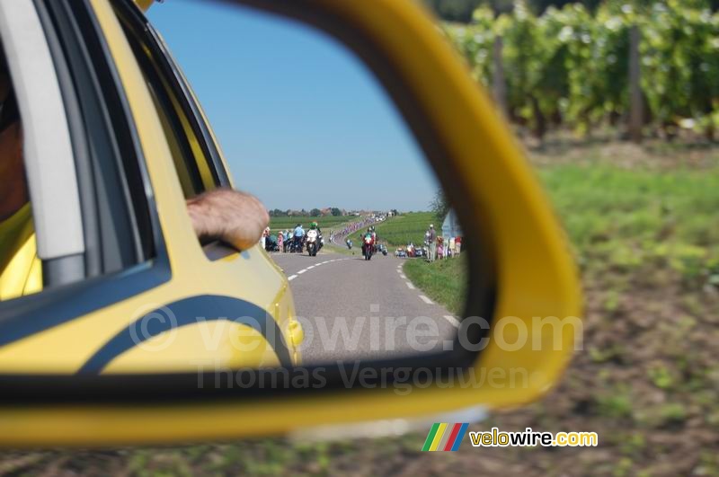 The pack of riders is coming - in the mirror of the Mavic car