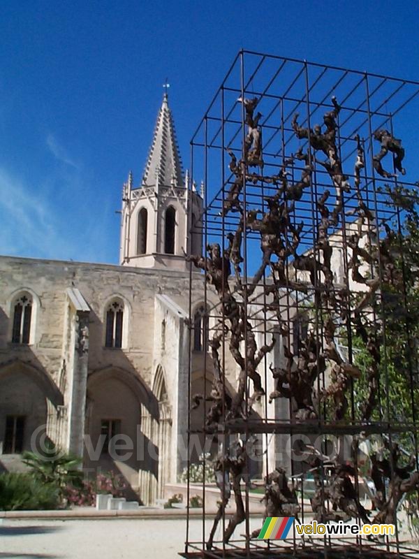Avignon: een kerk met op de voorgrond een kunstwerk gemaakt van metalen constructies en druivenranken