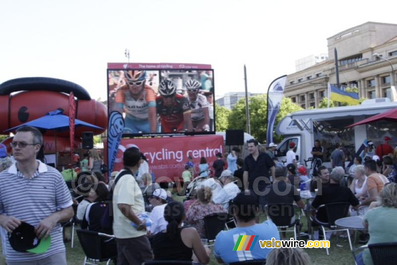 People watching the race summary on a big screen in the TDU village